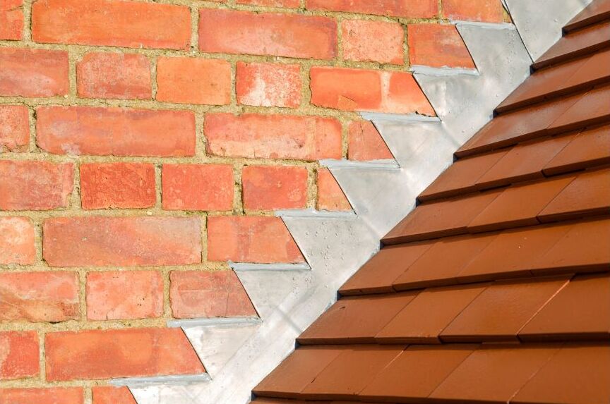 Roof flashing against red brick on a roof.